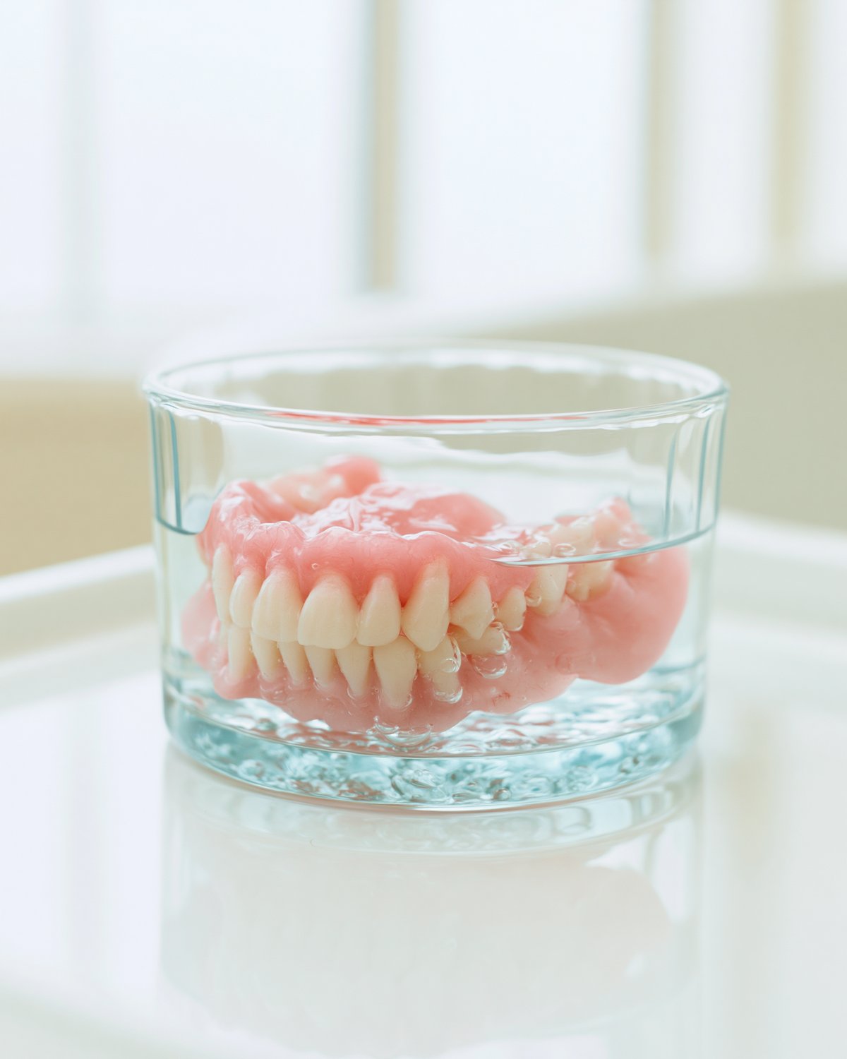 A denture soaking in a glass of water.